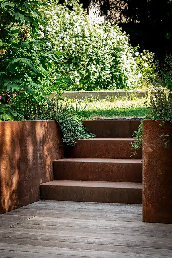 Escalier et muret en acier corten délimitant le jardin et la terrasse bois