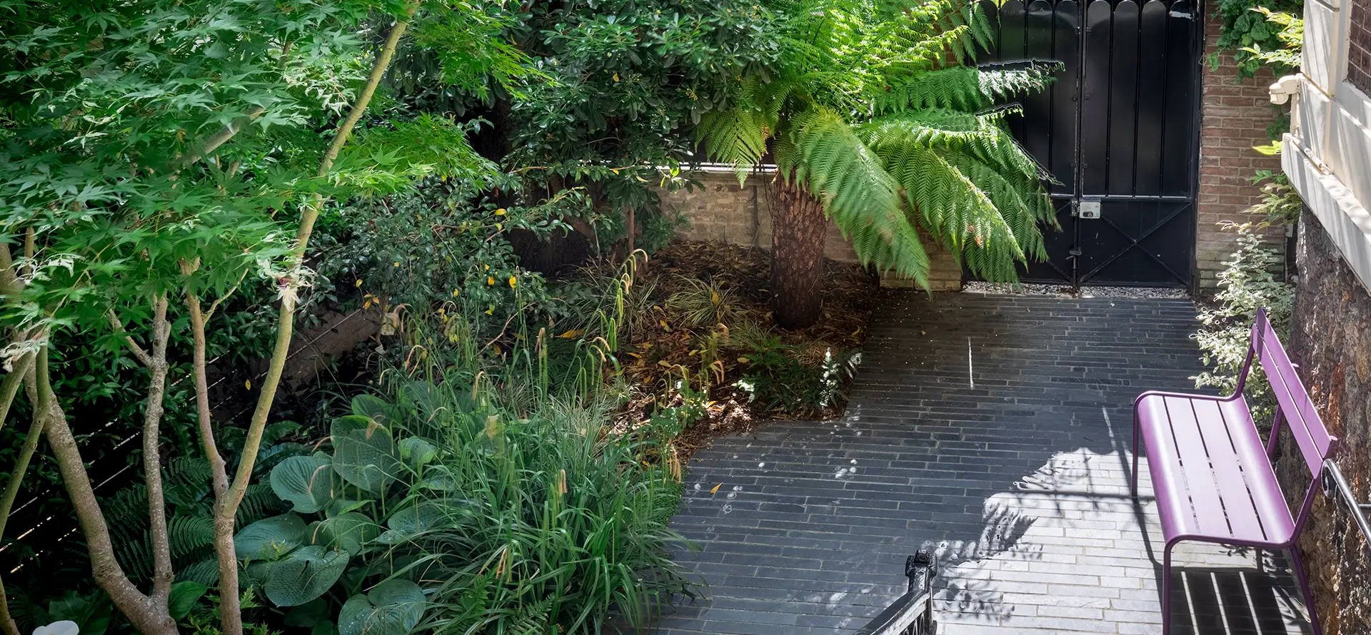 Jardin de ville avec son pavage d'ardoise et ses massifs luxuriants
