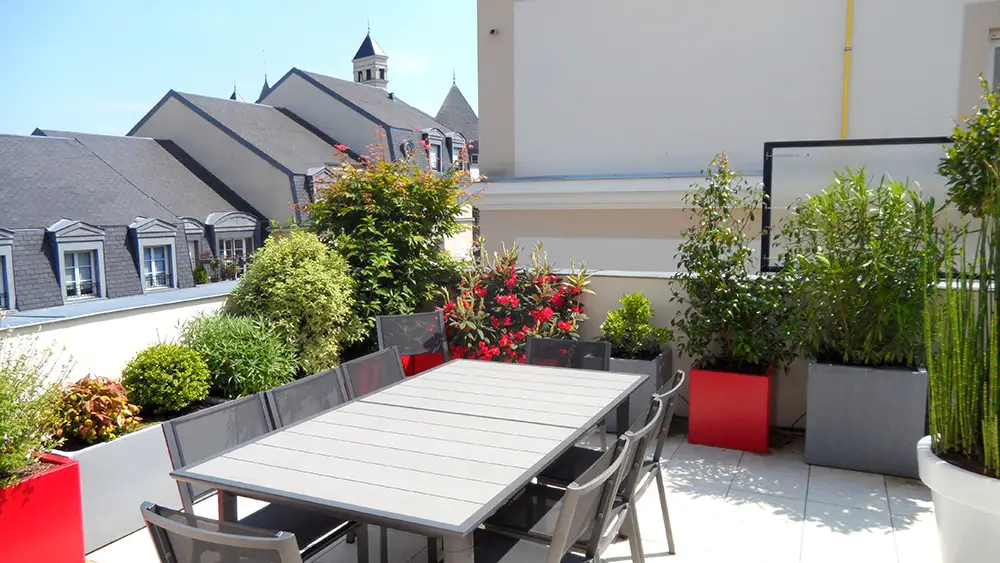 Espace repas entouré des bacs gris et rouge sur toit terrasse